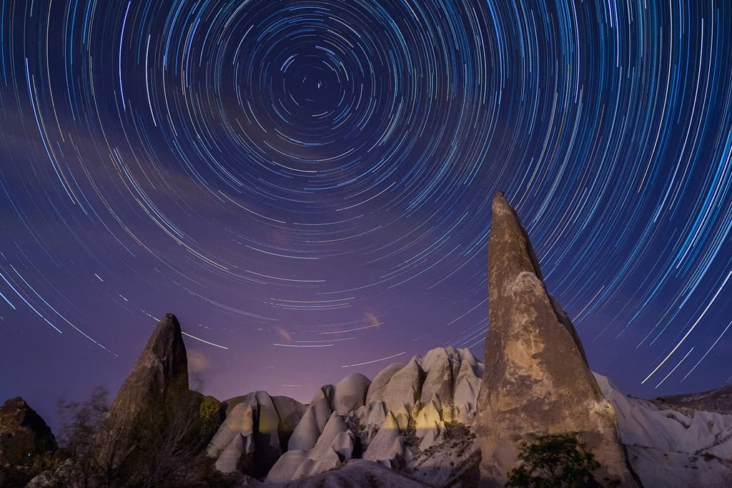 Long exposure night photography in Cappadocia with fairy chimneys and stars on the sky.